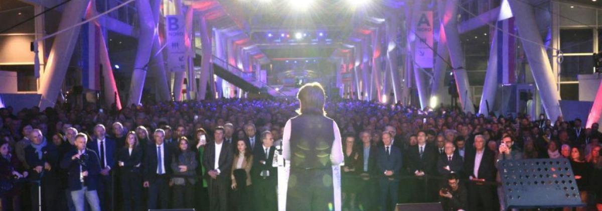 Martine Vassal vue de dos sur scène face à une foule nombreuse dans un grand hall éclairé