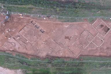 Vue aérienne d’un site archéologique montrant les fondations d’une villa romaine et plusieurs zones de fouilles