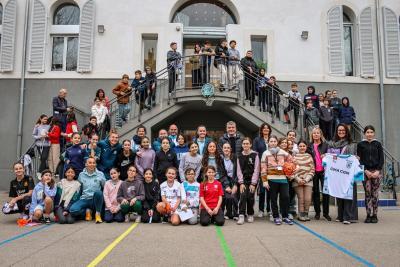 Une grande photo de groupe prise dans la cour d’un collège, réunissant des élèves, des enseignants et des athlètes féminines, dans le cadre d’un événement sportif. - Agrandir l'image 16 sur 16, fenêtre modale