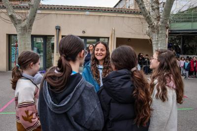 Une joueuse de l'Olympique de Marseille, souriante, échange avec un groupe de jeunes filles dans la cour d'un collège - Agrandir l'image 11 sur 16, fenêtre modale