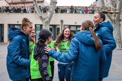 Des joueuses de l'Olympique de Marseille et des collégiennes partagent un moment de joie et de complicité après une activité sportive, sous le regard enthousiaste des autres élèves réunis sur la terrasse. - Agrandir l'image 7 sur 16, fenêtre modale