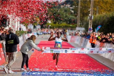 Coureuse franchissant la ligne d’arrivée de la course Marseille-Cassis sous une pluie de confettis rouges et blancs, avec un tapis rouge au sol et des spectateurs derrière les barrières. - Agrandir l'image 12 sur 12, fenêtre modale