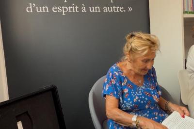 Personne âgée lisant un livre lors de l'inauguration de la maison du Bel Âge - Agrandir l'image 6 sur 7, fenêtre modale