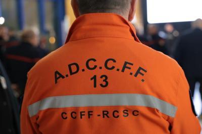 Un adulte de dos porte une veste orange vif avec des inscriptions noires “A.D.C.C.F.F. 13” et “CCFF‑RCSC”. Il se trouve dans un environnement intérieur animé, entouré d’autres personnes en uniformes sombres. La scène semble être une réunion ou un regroupement professionnel. - Agrandir l'image 3 sur 18, fenêtre modale