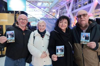 Groupe de personnes posant ensemble et tenant des photos souvenirs dans un hall d’événement - Agrandir l'image 8 sur 20, fenêtre modale