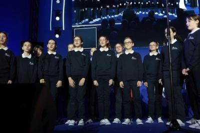 Groupe d’enfants en tenue uniforme alignés sur scène lors d’une prestation, avec écran géant en arrière-plan - Agrandir l'image 19 sur 20, fenêtre modale