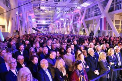 Grande foule rassemblée dans un hall éclairé en violet et bleu pour un événement officiel - Agrandir l'image 5 sur 20, fenêtre modale