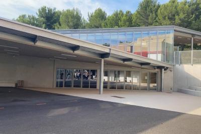 Vue extérieure d’un bâtiment moderne avec de grandes baies vitrées et un auvent couvrant l’entrée. Des arbres sont visibles en arrière-plan. - Agrandir l'image 1 sur 6, fenêtre modale