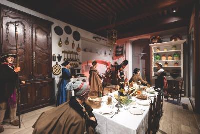 gros plan sur une reconstitution d'une salle à manger provençale avec des casseroles aux murs des placards et une grande tablée couverte de mets provençaux - Agrandir l'image 2 sur 3, fenêtre modale