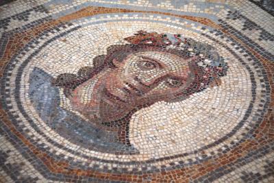 Photo montrant une mosaïque représentant un portrait de visage féminin, réalisée avec la technique de l'opus tessellatum, typique de l'Empire romain. Les détails et les couleurs mettent en valeur l'artisanat de l'époque. - Agrandir l'image 2 sur 4, fenêtre modale