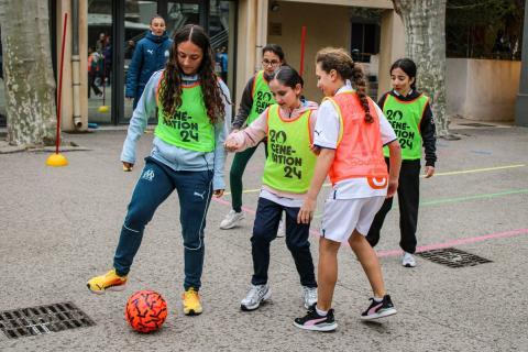 Une joueuse de l'Olympique de Marseille initie des collégiennes au football dans le cadre du programme 'Génération 2024', favorisant l'apprentissage et le partage des valeurs du sport.