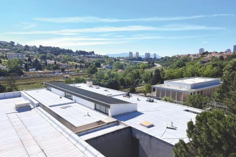 Les toits du collège Jean-Moulin (Marseille, 15e) en vue aérienne. Il fait beau et on aperçois Marseille dans le fond.